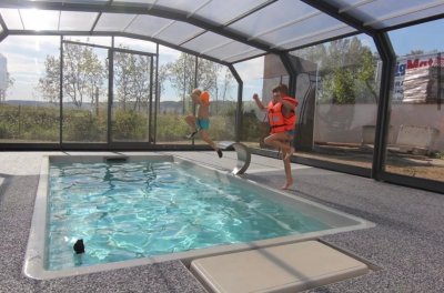 Крытый прямоугольный бассейн с прозрачной крышей и детьми в плавательных жилетах